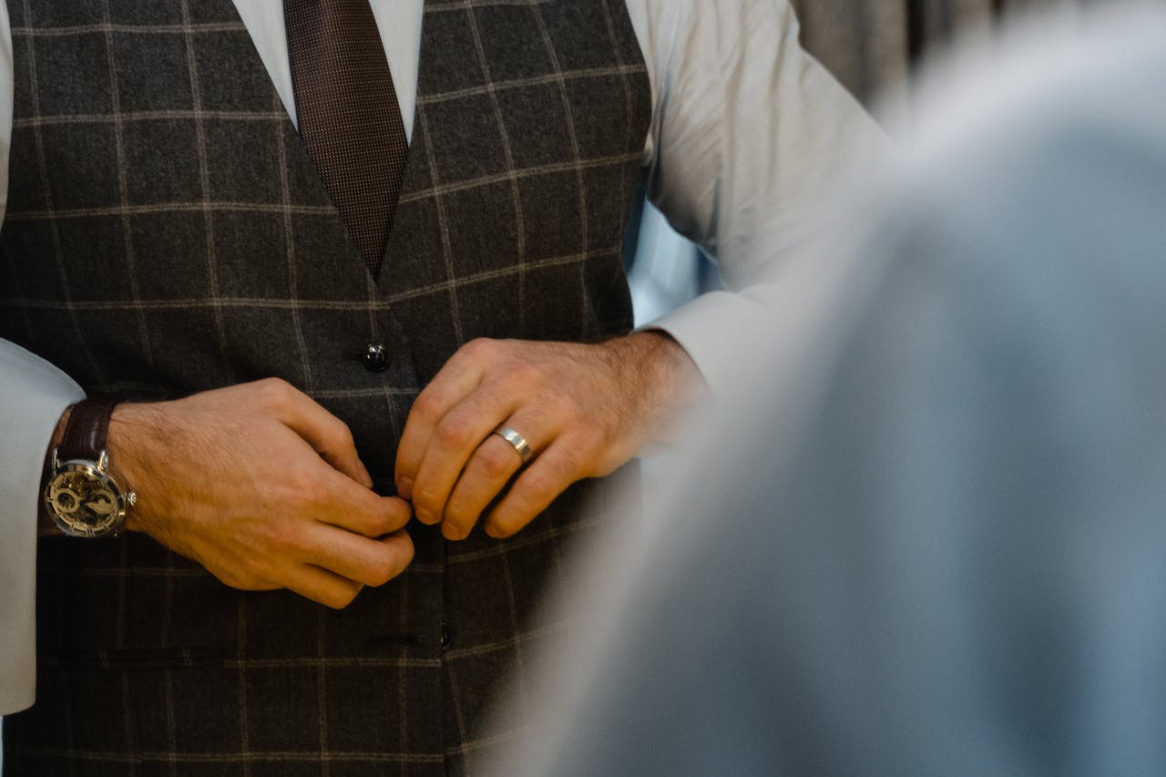 Close-up of a man adjusting his elegant suit jacket with stylish accessories.